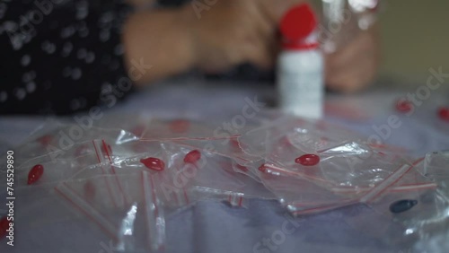 Nurse hands put Vitamin A supplement capsule in to plastic packaging. Close up selective focus photo