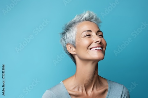 Cheerful young woman with short blue hair on blue background.