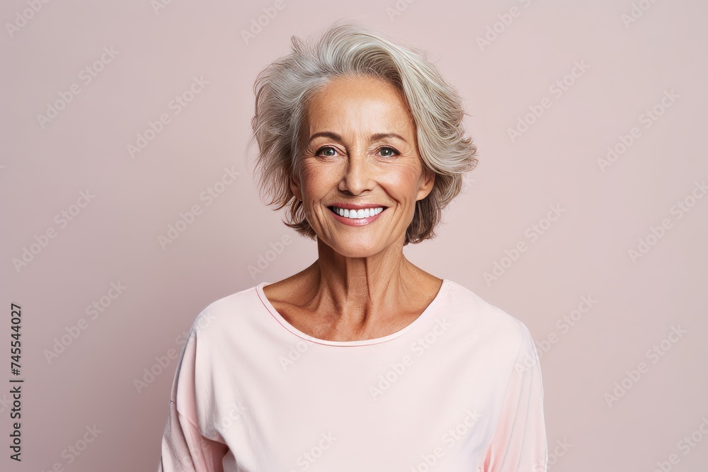 Happy senior woman. Portrait of beautiful mature woman smiling and looking at camera while standing against pink background Happy senior woman. Portrait of beautiful mature woman smiling and looking at camera while standing against pink background