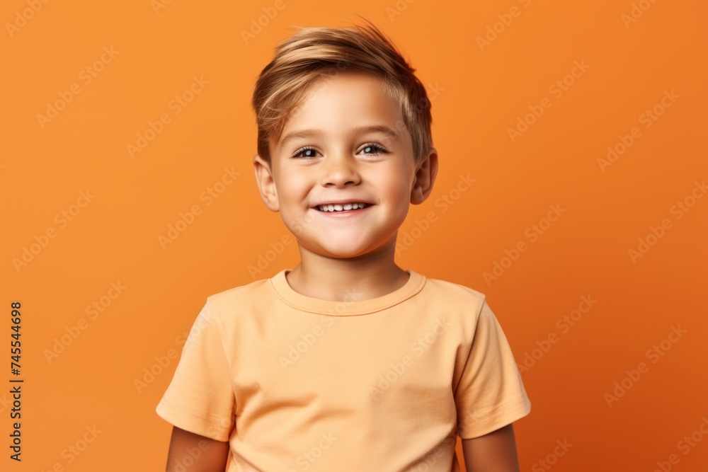 Portrait of a cute little boy smiling and looking at camera over orange background Portrait of a cute little boy smiling and looking at camera over orange background