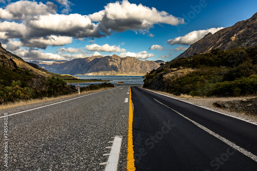 Beautiful road between the mountains with lake in the background of New Zealand