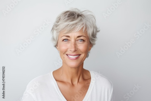 Closeup portrait of a happy senior woman looking at camera against grey background