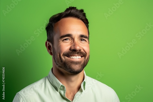 Handsome man with beard and mustache smiling against a green background