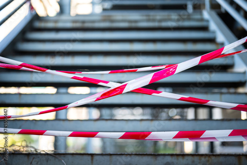 Close-up at the red-white barricade tape, using for secure the restricted area with background of banister route. 