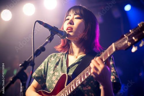 A young Japanese woman is playing the guitar during a live band event