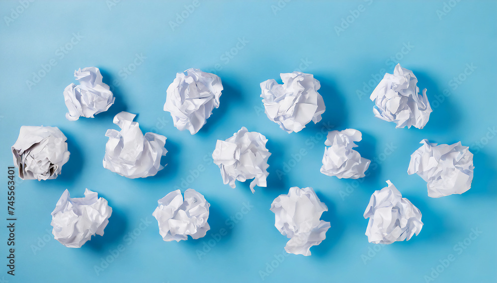 Crumpled white paper balls scattered randomly on a light blue background, symbolizing ideas, brainstorming, and creativity. Crumpled white paper balls scattered randomly on a light blue background, symbolizing ideas, brainstorming, and creativity.