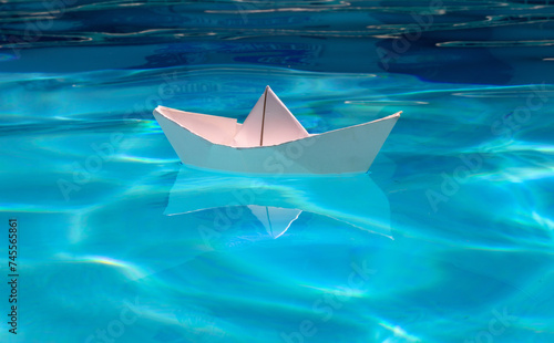 Origami ship. White paper boat into the clear sea water. © Volodymyr