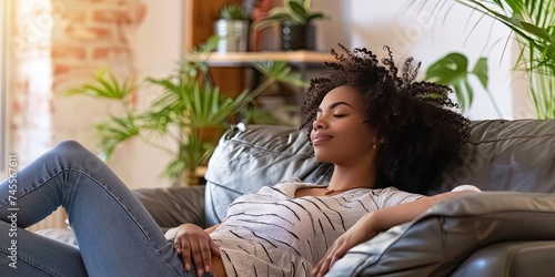 African American Woman wearing trendy clothes relaxing on the couch after a hard day's work. Taking a break and resting on comfortable furniture. 