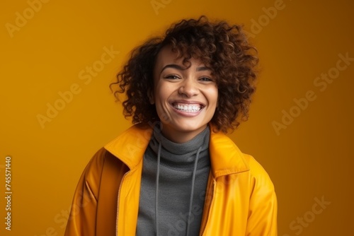 Portrait of a happy young african american woman in yellow jacket on yellow background © Iigo