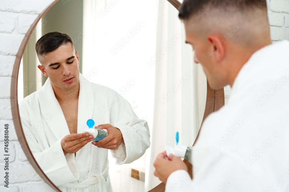 Handsome young man using cotton pad on his face in bathroom Handsome young man using cotton pad on his face in bathroom