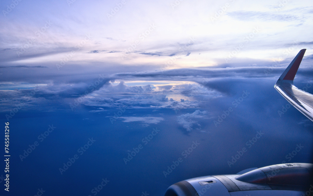 View from airplane window with wing and engine, during sunset time.