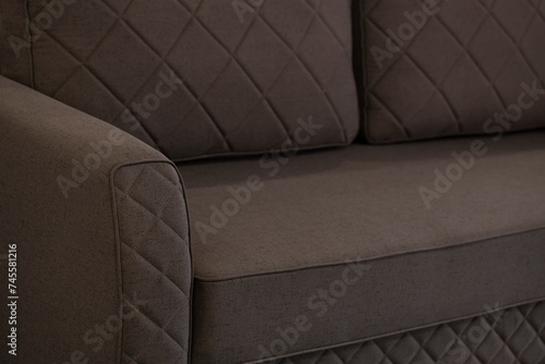 Quilted brown sofa made of mating. Close-up of stitched lines on a soft volumetric sofa in the form of a diamond-shaped pattern. Upholstered furniture made of spotted brown-black netting fabric.