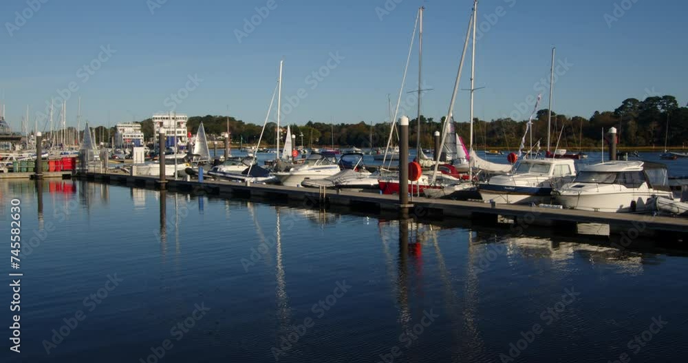 multiple sailing dinghies sailing past moored up motor yachts and out of frame on Lymington river multiple sailing dinghies sailing past moored up motor yachts and out of frame on Lymington river