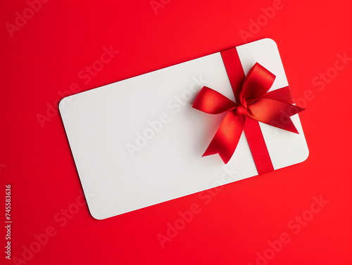 Blank white gift card with red ribbon bow isolated on red background. Minimal mockup 3D rendering. Gift and celebration concept for design, banner, and print. Flat lay composition with copy space