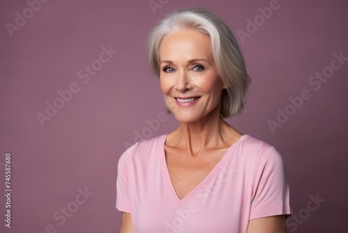 Portrait of a beautiful senior woman smiling at the camera on a purple background