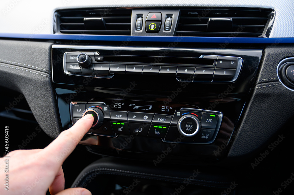 Close up of a hand pressing the climate controls of a car Close up of a hand pressing the climate controls of a car
