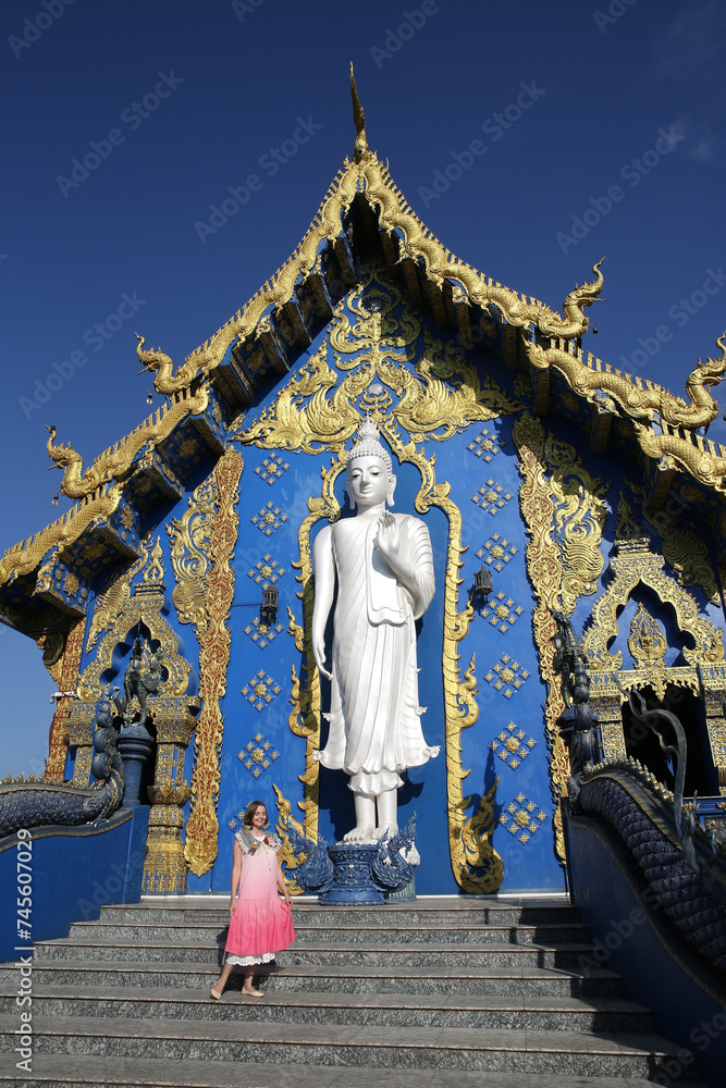 Tourist woman, fashion girl and Wat Rong Suea Ten, Blue Temple in Chiang Rai city, Thailand. Religious traditional national Thai architecture. Landmark, architectural monument. Buddhist temple, sight