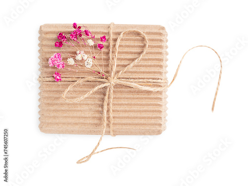 Top view of single craft carton disposable gift box tied with string decorated with dried red and pink gypsophila flowers isolated on white background used for greeting on holidays celebration