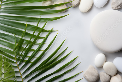 Top view of natural white stones and palm leaves on a white background. Spa background