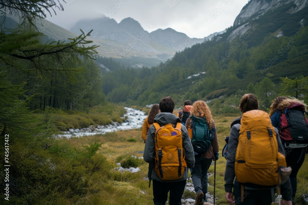 Group of hikers with backpacks trekking in mountainous landscape by a river.
