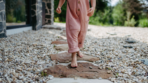 Close up of little girl walking barefoot near the forest cotage,weekend time during summer day. photo