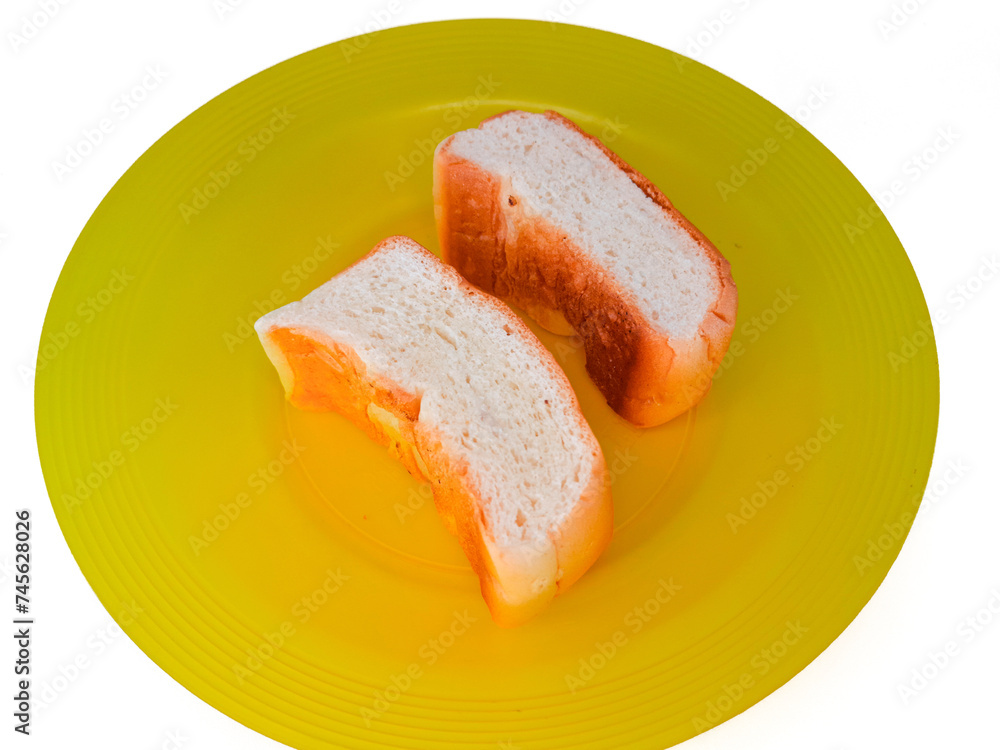 two slices of bread on a yellow plastic plate, isolated on a white background, concept of hunger, poverty and inflation impacting society or humans.