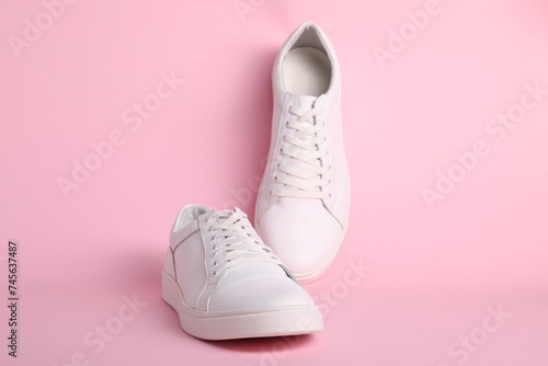 Pair of stylish white sneakers on pink background