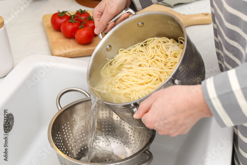 Fotografie Woman draining pasta into colander at sink, closeup
