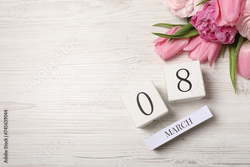 International Women's day - 8th of March. Block calendar and beautiful flowers on white wooden table, flat lay. Space for text