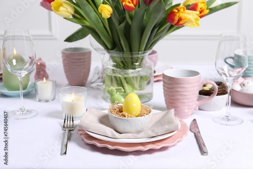 Festive table setting with painted egg in decorative nest. Easter celebration