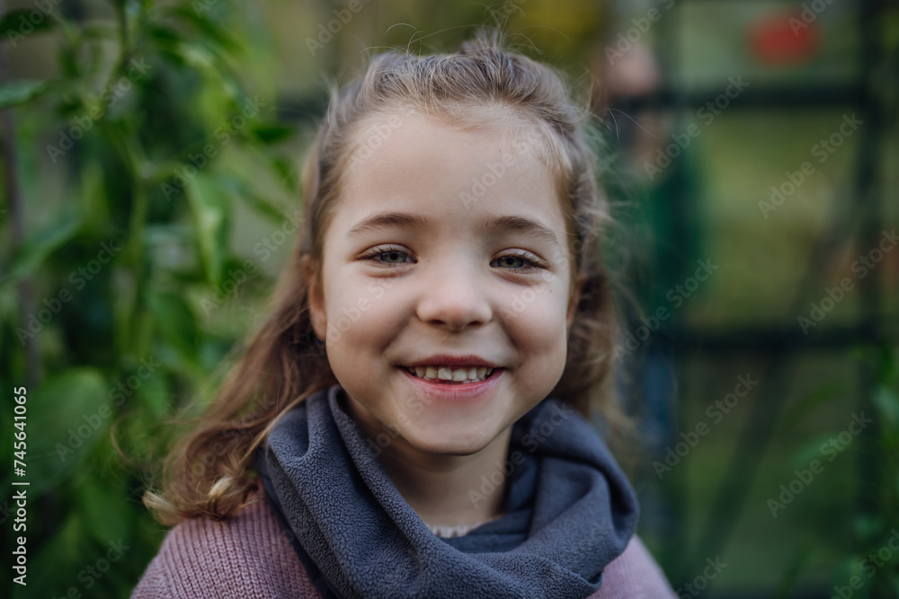 Portrait of girl standing in greenhouse, during first spring days. Concept of water conservation in garden and family gardening. Portrait of girl standing in greenhouse, during first spring days. Concept of water conservation in garden and family gardening.