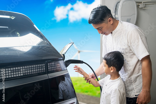 Asian father teaches his son how to charge an EV at home