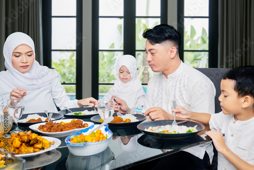 Young muslim family of father, mother, son, and daughter eating together at home