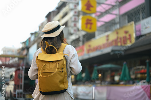 Back view of female tourist with backpack walking at Chinatown street in Chiang Mai, Thailand