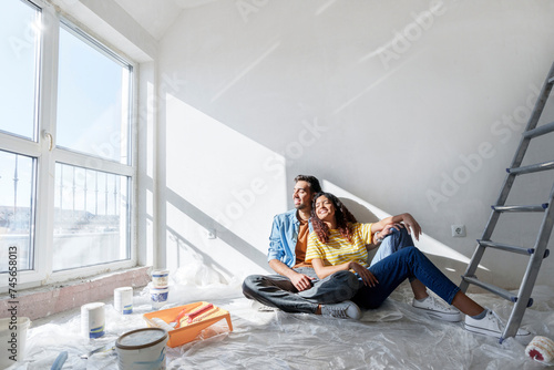 Happy couple sitting on floor at new home photo