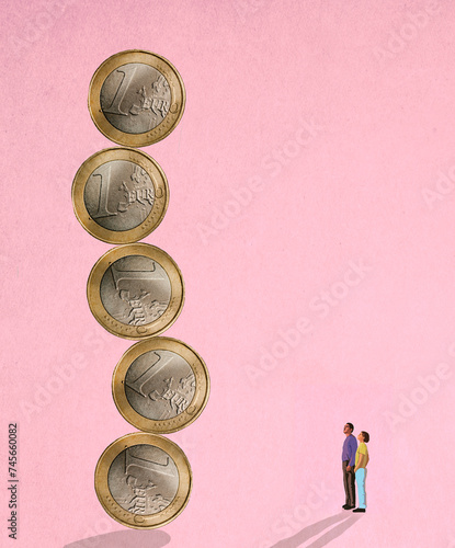 Two people looking at unstable column of oversized one Euro coins photo