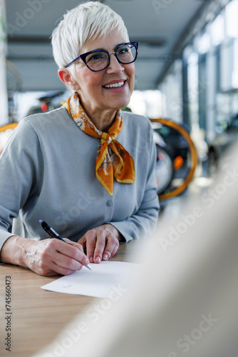 Happy senior woman doing paperwork at desk photo