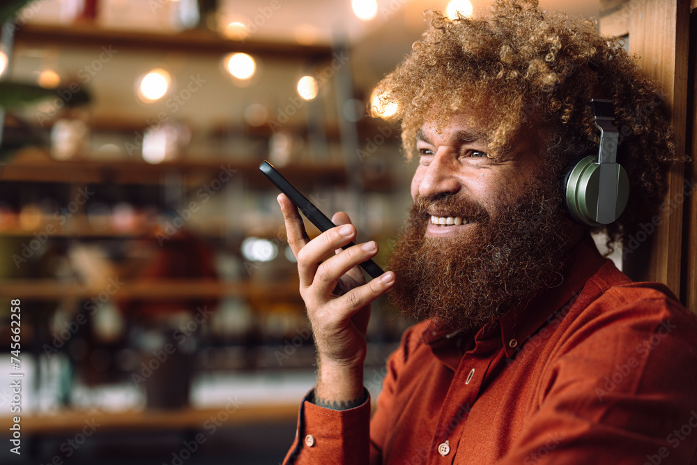 © Westend61 - Smiling businessman wearing wireless headphones listening to music and holding smart phone © Westend61 - Smiling businessman wearing wireless headphones listening to music and holding smart phone