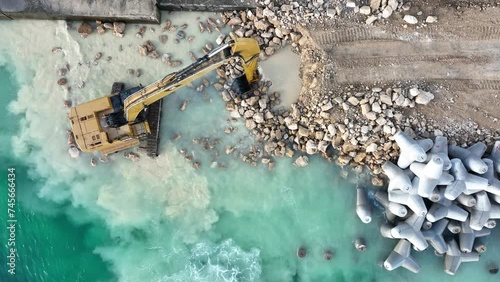 Aerial view of waterfront construction site with excavator. Excavator working on a breakwater construction photo