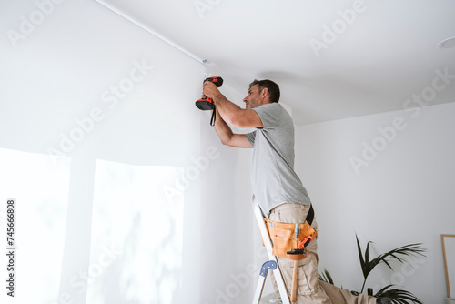 Repairman drilling hole in wall at home photo