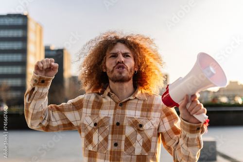 Angry man shouting with megaphone under sky photo