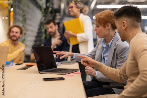 Businessman and businesswoman pointing at laptop in office photo