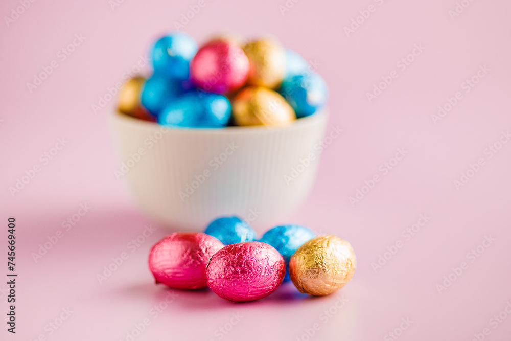 Easter chocolate eggs wrapped in aluminium foil on pink background. Easter chocolate eggs wrapped in aluminium foil on pink background.