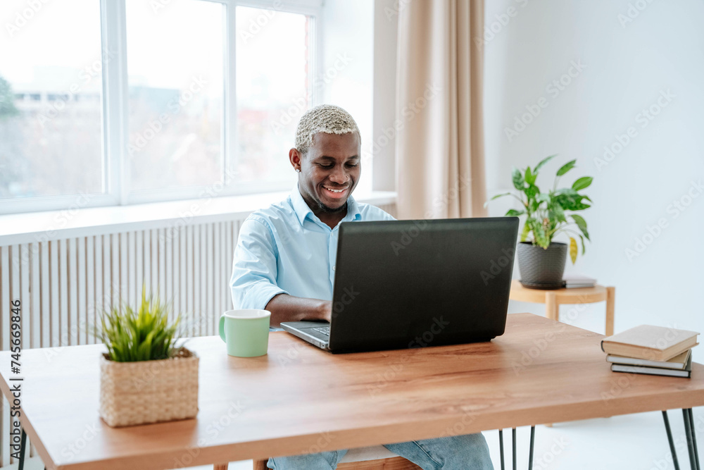 Smiling freelancer working on laptop at desk in home office Smiling freelancer working on laptop at desk in home office