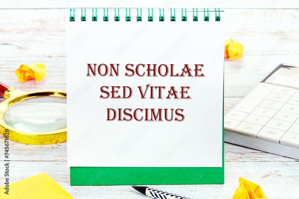Non scholae sed vitae discimus It is translated from Latin as We study not for school, but for life. It is written on a standing notebook - obrazy, fototapety, plakaty 