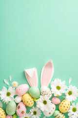 Easter crafting idea: Overhead vertical shot of vibrant eggs, cute bunny ears, and fresh daisy blooms on a teal backdrop with space for your text or advertisement