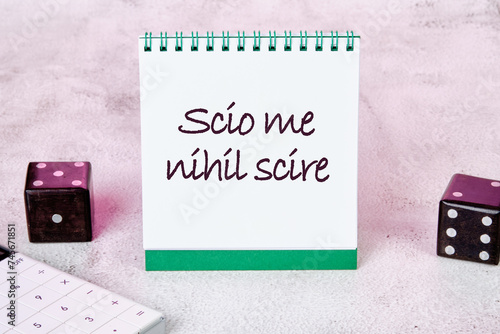 Scio me nihil scire It is translated from Latin as I know I don't know anything It is written on a white sheet of a notebook photo