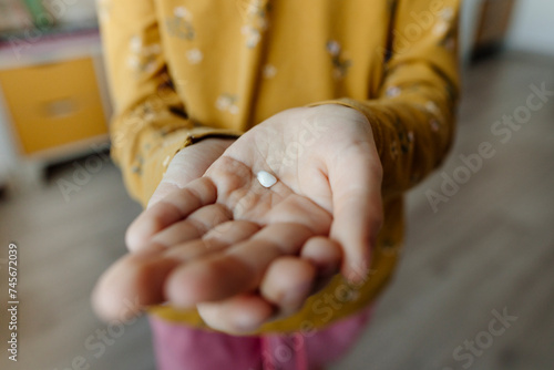 Hand of girl holding broken tooth at home photo