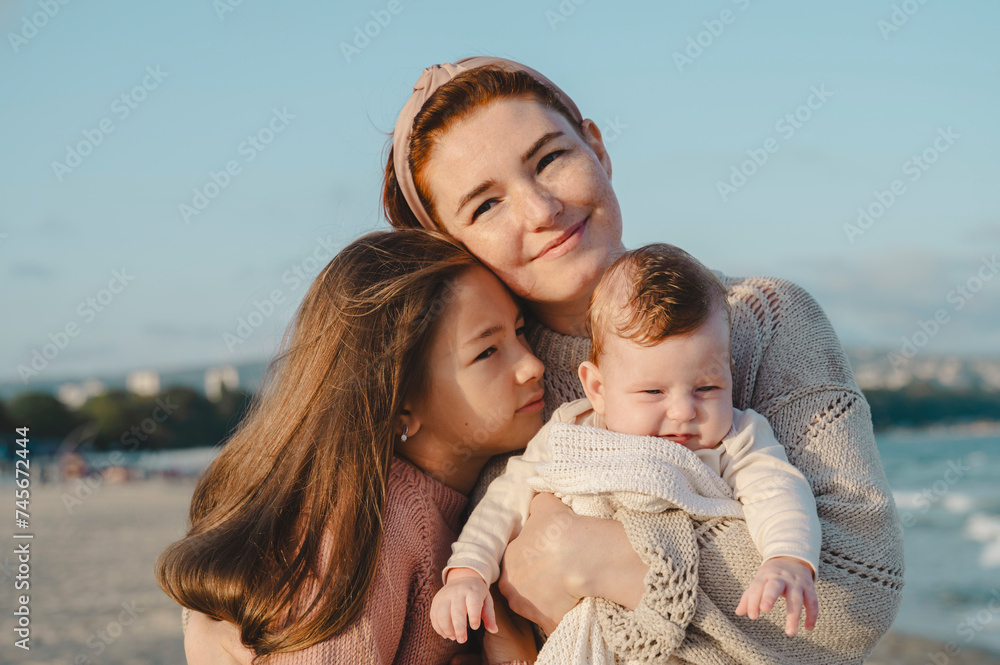 Smiling mother spending leisure time with daughters at beach on sunny day Smiling mother spending leisure time with daughters at beach on sunny day