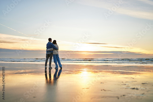 Young couple embracing at coastline on ocean beach photo
